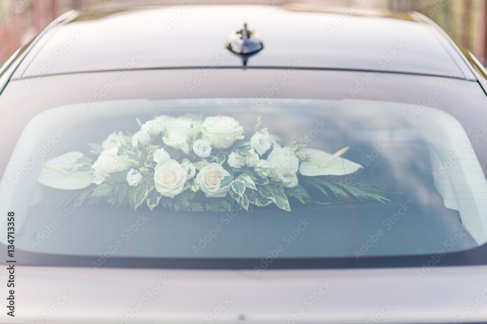 Foto Stock Composizione di fiori posta sulla cappelliera della macchina  degli sposi vista attraverso il lunotto | Adobe Stock