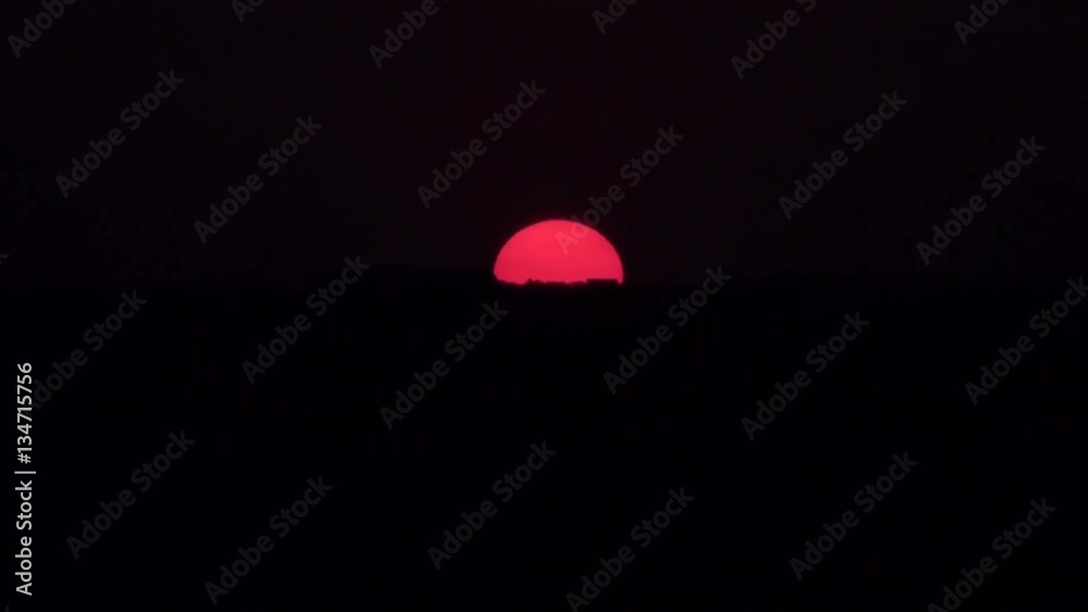 Red sun set time laps in a very dark scene . Red sun set time laps in a very dark scene .
