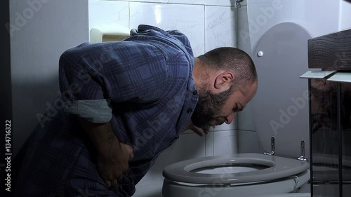  young man with beard vomits abundantly in the bathroom photo