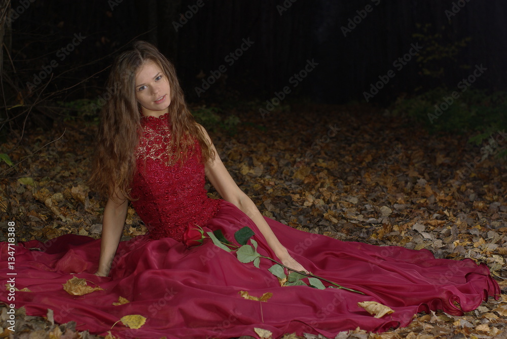 Fototapeta premium Girl in a red dress with a rose in her hand