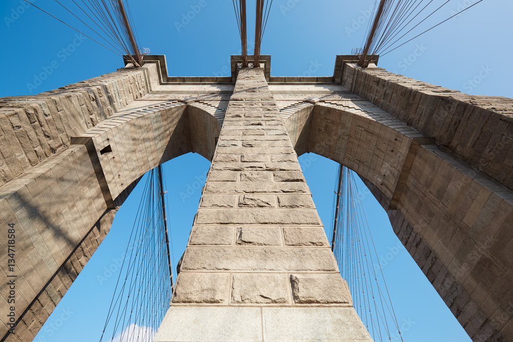 Fototapeta premium Brooklyn Bridge pillar low angle view, blue sky in New York