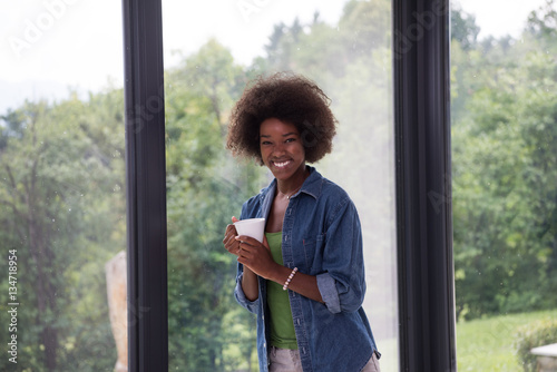 African American woman drinking coffee looking out the window