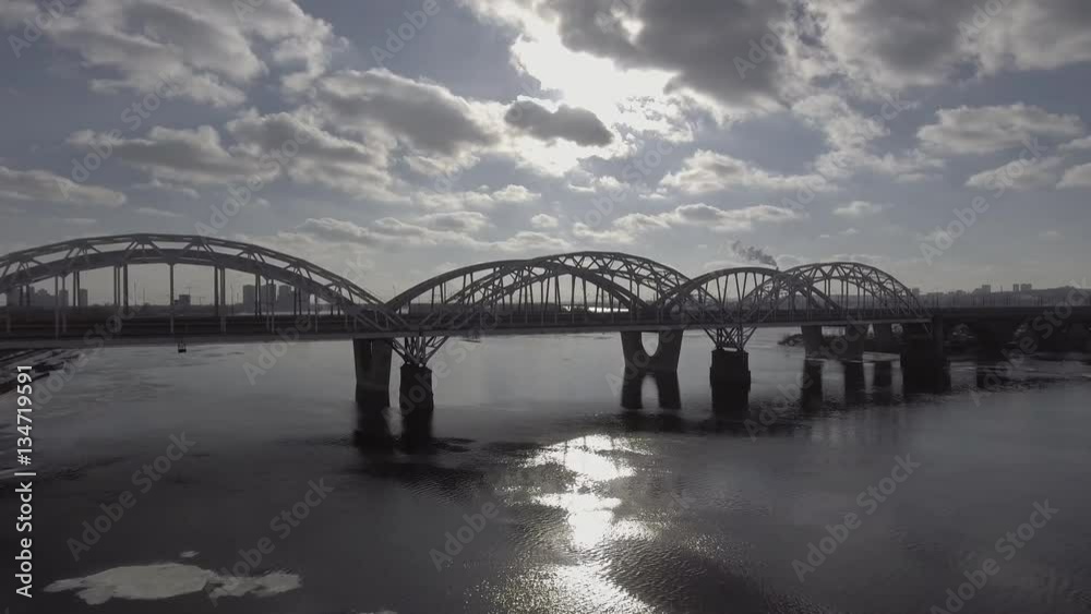 Shooting with air, railway bridge near the car ride, the river is covered with ice, the sun shining brightly. Aeria 4k video Shooting with air, railway bridge near the car ride, the river is covered with ice, the sun shining brightly. Aeria 4k video