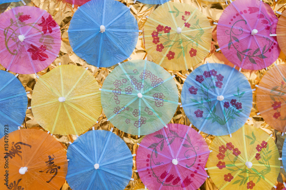 Summer concept background, colorful paper umbrella on gold paper background, outdoor day light Summer concept background, colorful paper umbrella on gold paper background, outdoor day light