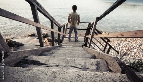Young man stands on coastal stairway