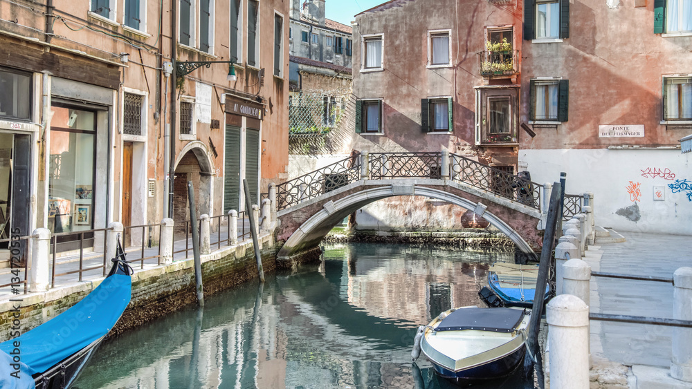 Venice, Italy - February 17, 2015:  Classical picture of the venetian canals with gondola across the canal.