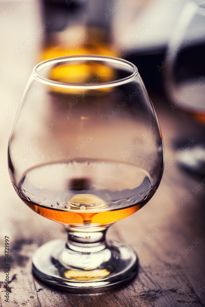 Glass whiskey cognac brandy or rum.One half full glasses of cognac on a wooden surface. Glass whiskey cognac brandy or rum.One half full glasses of cognac on a wooden surface.