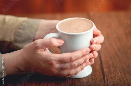 Female hands holding hot cup of cacao