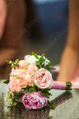 Little pink bouquet of peonies lies on glass table