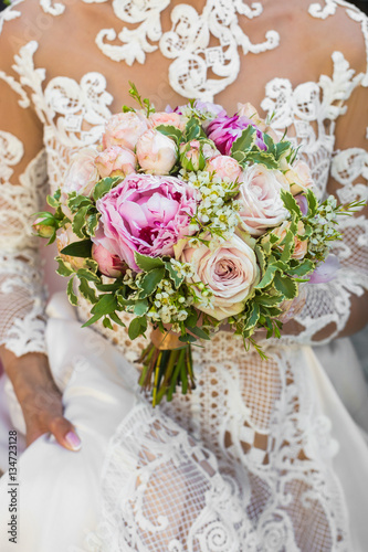 Gorgeous wedding bouquet made of peonies and roses and held by b
