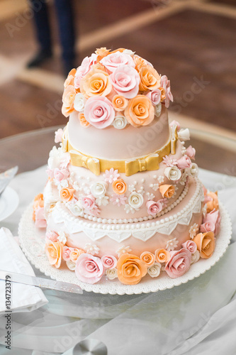 Delicious wedding cake decorated with orange and pink roses stan