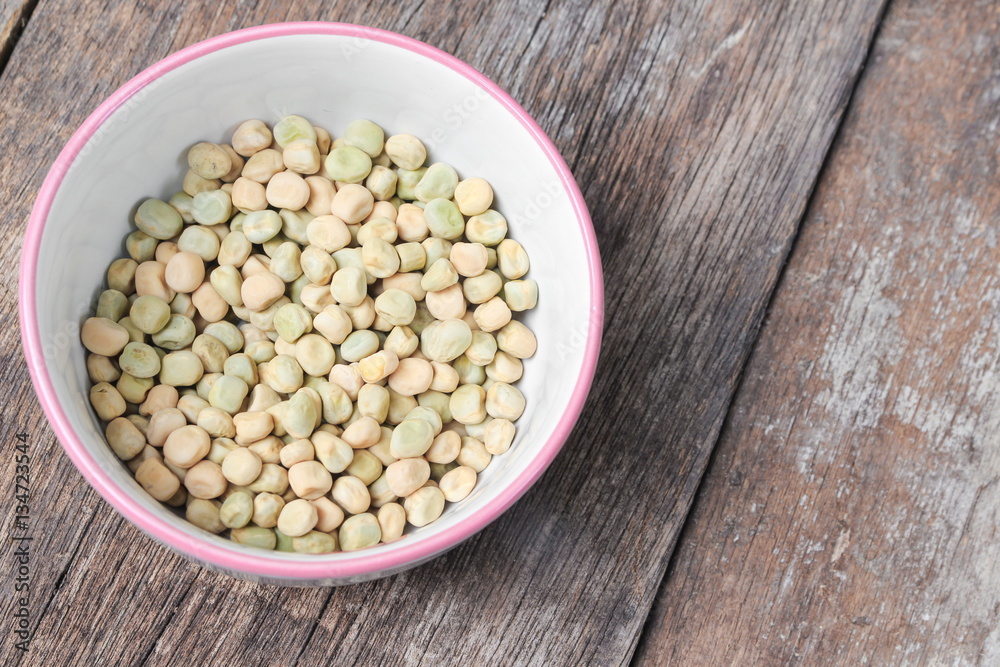 dry green peas, sugar pea in bowl on the wood board background.