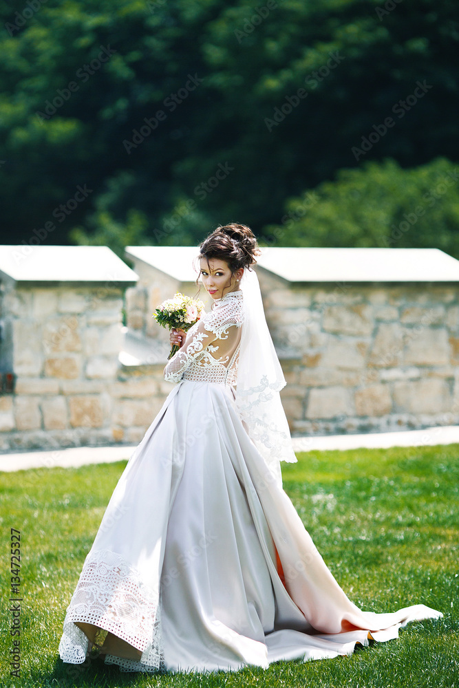 Awesome bride in lace dress looks over her shoulder posing on th Awesome bride in lace dress looks over her shoulder posing on th