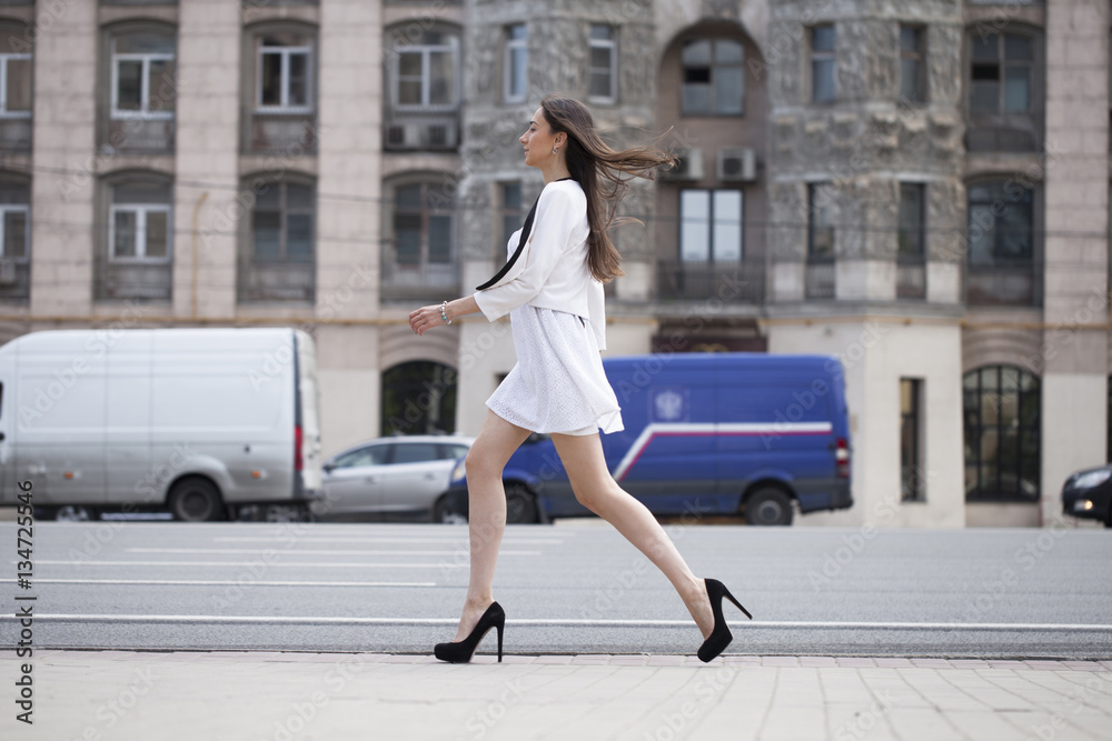 Young beautiful brunette woman in white dress walking on the str Young beautiful brunette woman in white dress walking on the str