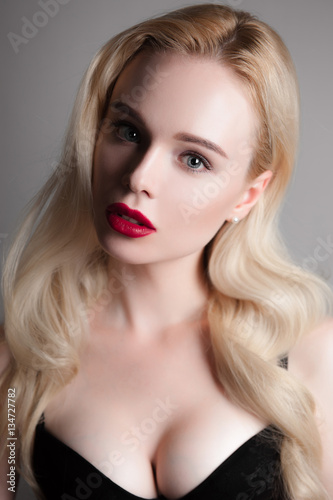 Beauty model girl with perfect make-up red lips and blue eyes looking at camera, wearing magenta bra. Portrait of attractive sexy young woman with blond hair. Fashion retouched close up shot.