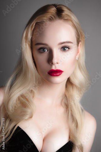 Beauty model girl with perfect make-up red lips and blue eyes looking at camera, wearing magenta bra. Portrait of attractive sexy young woman with blond hair. Fashion retouched close up shot.