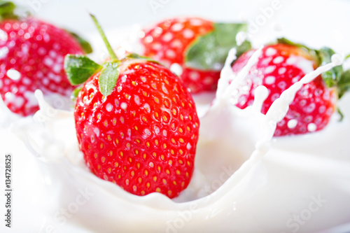 Strawberries falling into fresh bowl of cream