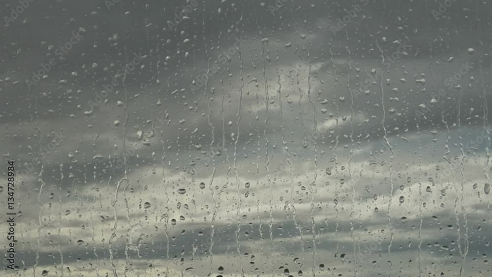 Rain drops on Window Pane with Gray Clouds Outside