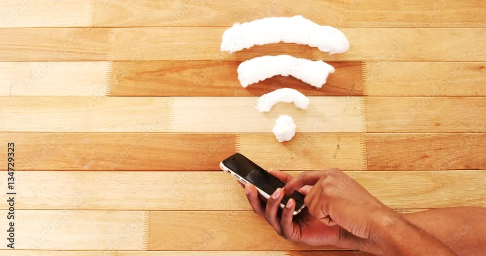 Hands using mobile phone with wifi sign against wooden background 4k