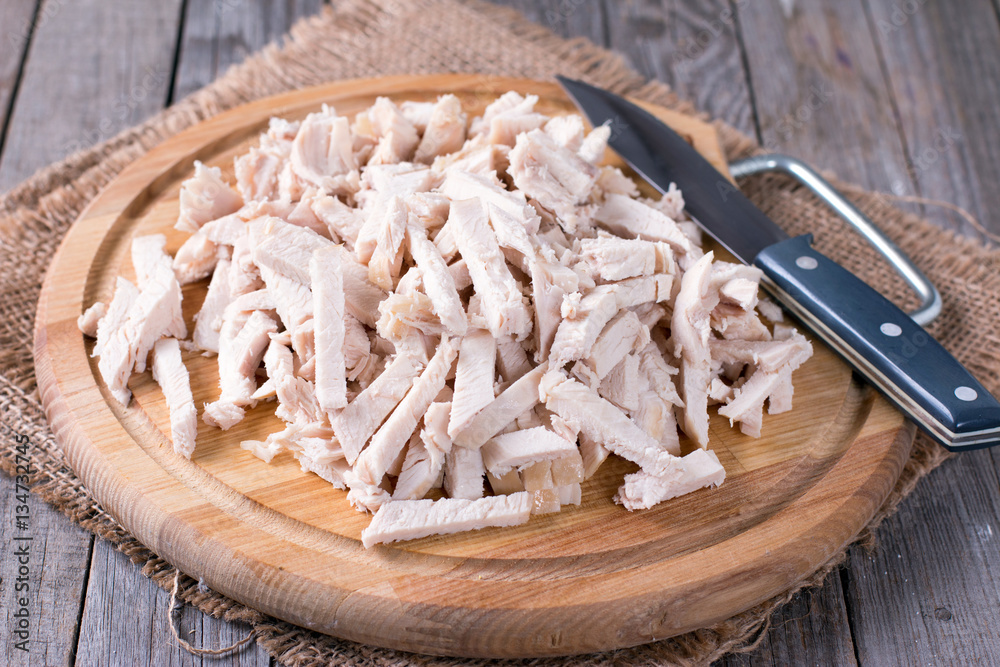 Pieces of boiled chicken breast on wooden background