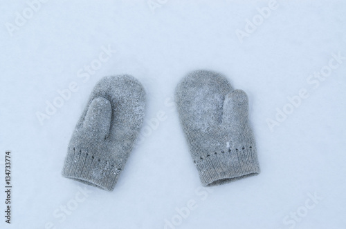 Slika na platnu Knitted woollen mittens on white snow in cold winter.