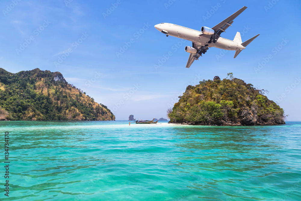 passenger airplane flying above small island in tropical sea.travel destinations concept
