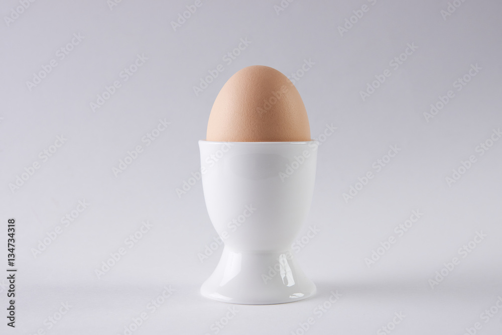 Brown egg in egg cup on white background Brown egg in egg cup on white background