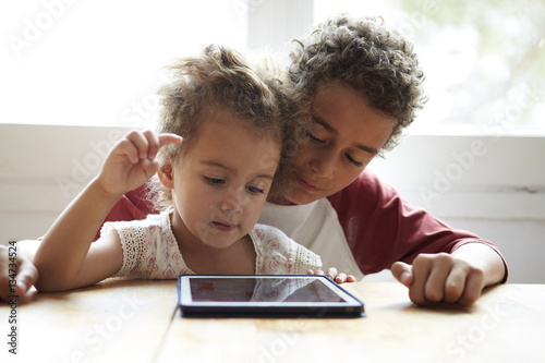 Children At Home Using Digital Tablet On Kitchen Table