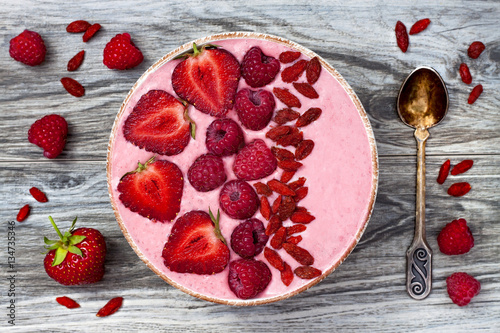Pink acai, maca powder smoothie bowl topped with sliced strawberries, raspberries and goji berries. Flat lay, copy space. Valentines Day superfood aphrodisiac meal