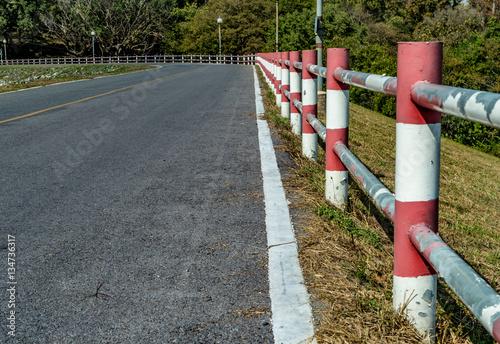 Asphalt road with red and white fence