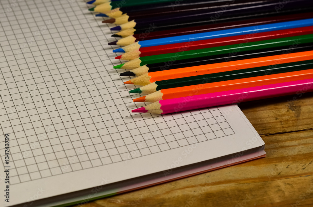 Fototapeta premium Notebook with colour pencils on the wooden table