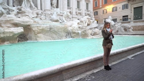 Travel girl trowing coin at Trevi Fountain, Rome, Italy for good luck. Happy young girl smiling traveling on vacation holiday in Europe.