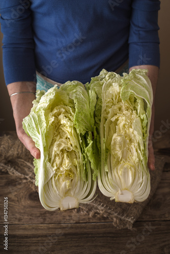 Woman holding two halves of the Chinese cabbage on the table