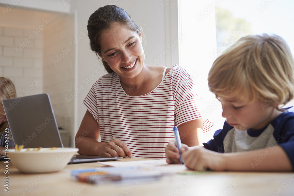 Mother watching son colouring at the kitchen table Mother watching son colouring at the kitchen table