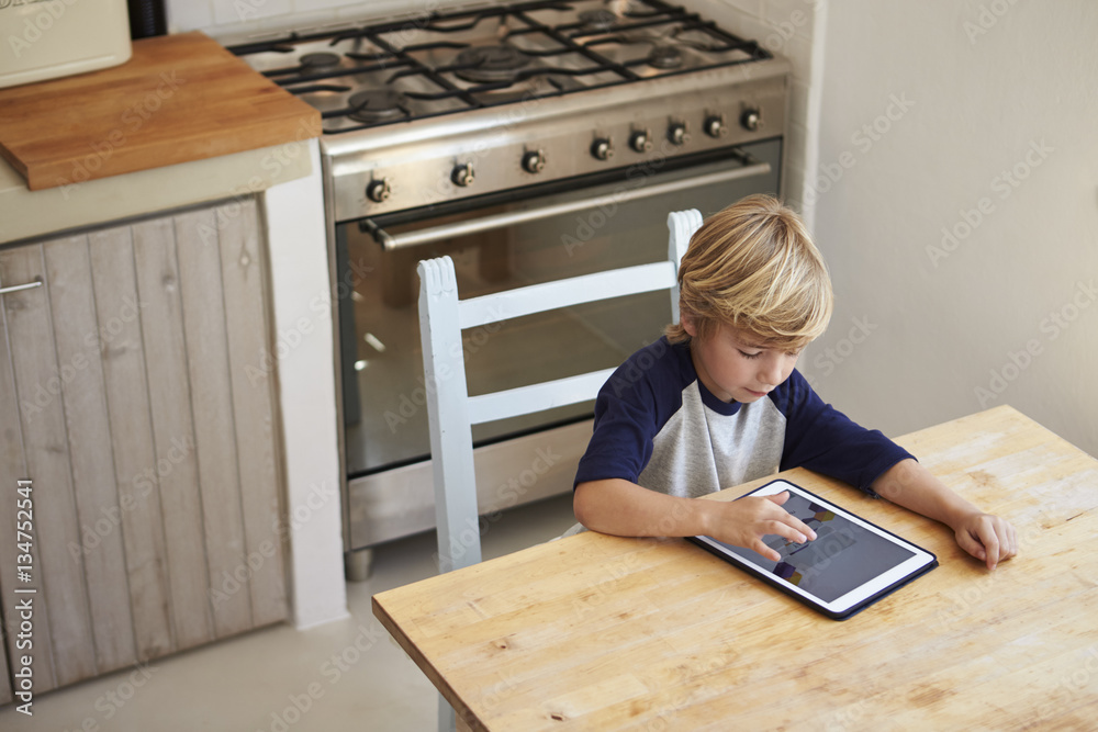 Young boy using tablet computer in kitchen, elevated view Young boy using tablet computer in kitchen, elevated view