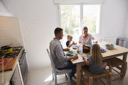 Family sitting down to eat lunch at kitchen table
