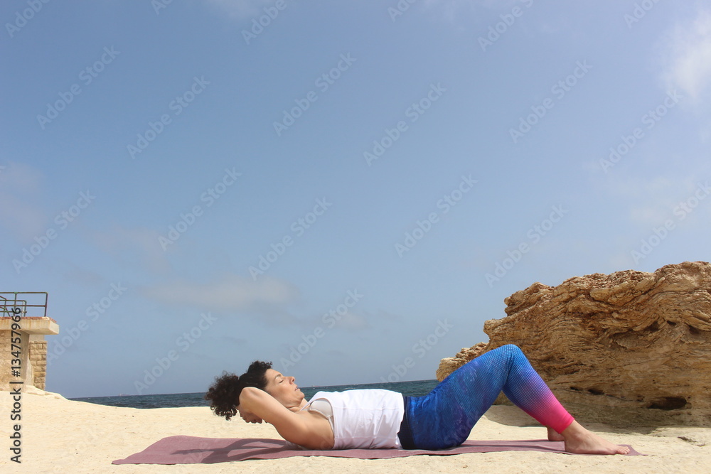 Mujer haciendo abdominales en la playa, chica entrenando al aire libre