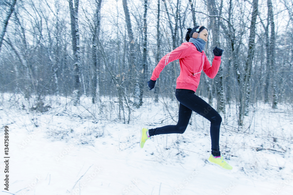 Running sport woman. Female runner jogging in cold winter forest wearing warm sporty running clothing and gloves headphones. Beautiful fit female fitness model. Running sport woman. Female runner jogging in cold winter forest wearing warm sporty running clothing and gloves headphones. Beautiful fit female fitness model.