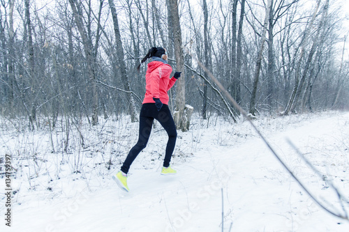 Running sport woman. Female runner jogging in cold winter forest wearing warm sporty running clothing and gloves headphones. Beautiful fit  female fitness model. © ekaterina_devis