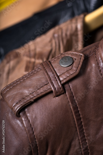 Different color leather jacket hanging on rack on blue background © sergmam