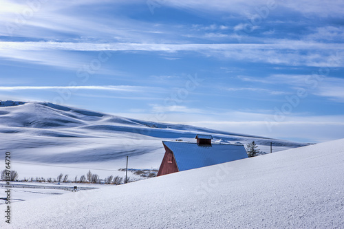 Photography The roof of a red barn peaks over a snowy hill in this winter vista in Moscow, Idaho