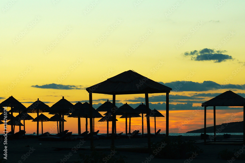 Sunset on the beach, the silhouettes of straw umbrellas and gazebos Sunset on the beach, the silhouettes of straw umbrellas and gazebos