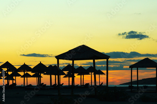 Sunset on the beach, the silhouettes of straw umbrellas and gazebos