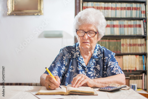Senior woman calculating budget at home.