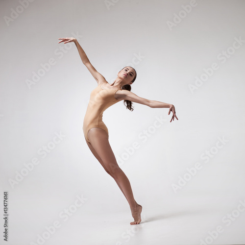 Fototapeta Naklejka Na Ścianę i Meble -  young beautiful dancer in beige swimsuit posing on isolated white studio background