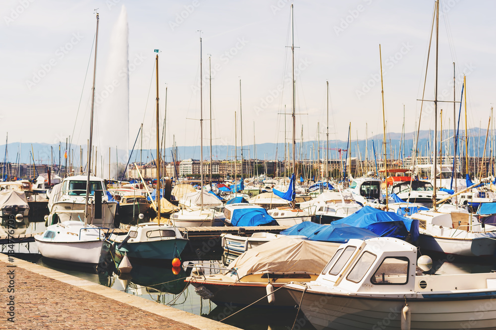 Geneva port with boats and Jet d'eau on background on a very sunny day, toned image