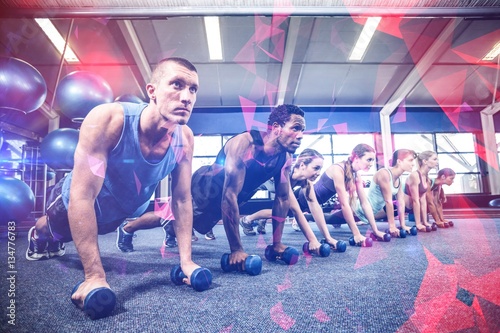 Fitness class in plank position with dumbbells