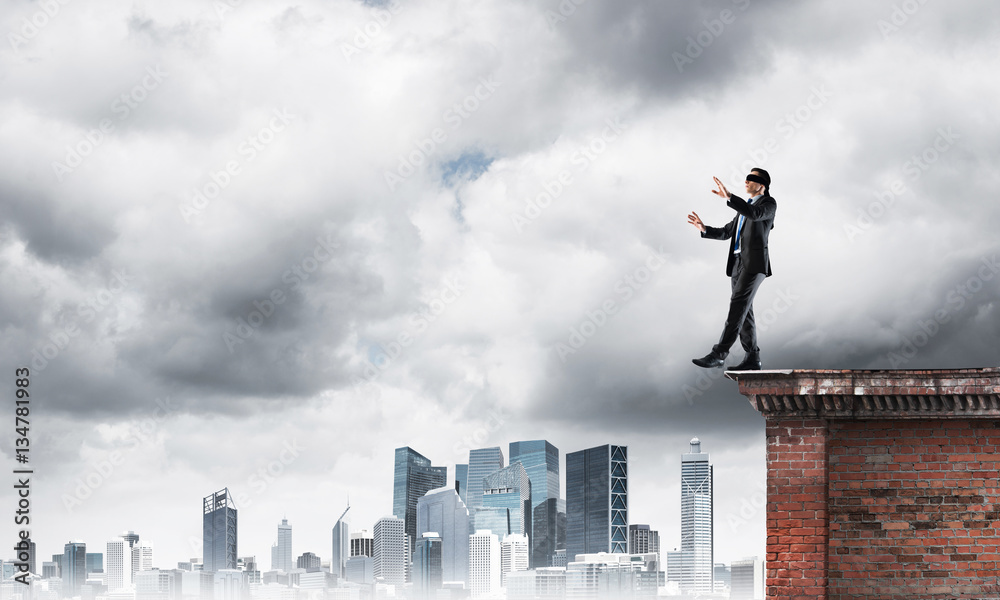 Danger and risk concept with businessman making step from edge Danger and risk concept with businessman making step from edge