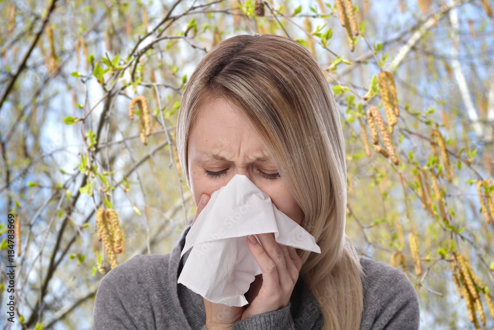 Pollen allergy, Springtime. Woman sneezing in a tissue Pollen allergy, Springtime. Woman sneezing in a tissue