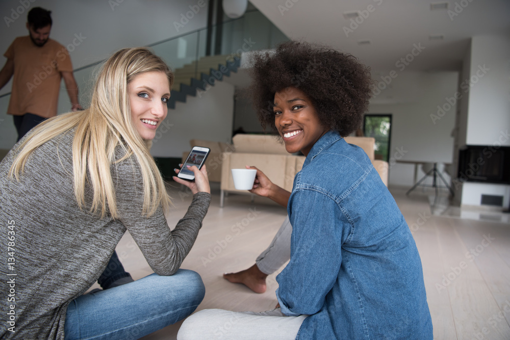 young multiethnic women sit on the floor and drinking coffee young multiethnic women sit on the floor and drinking coffee